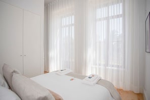 Una camera d'albergo con un letto, un armadio e tende leggere.