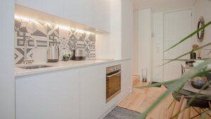 Une cuisine moderne avec des meubles blancs, un évier en acier inoxydable et un four encastré.