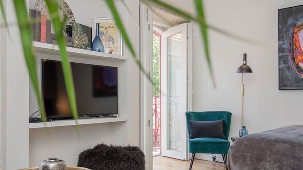 Un salon moderne comprenant un téléviseur, un canapé, un fauteuil et une lampe sur pied.