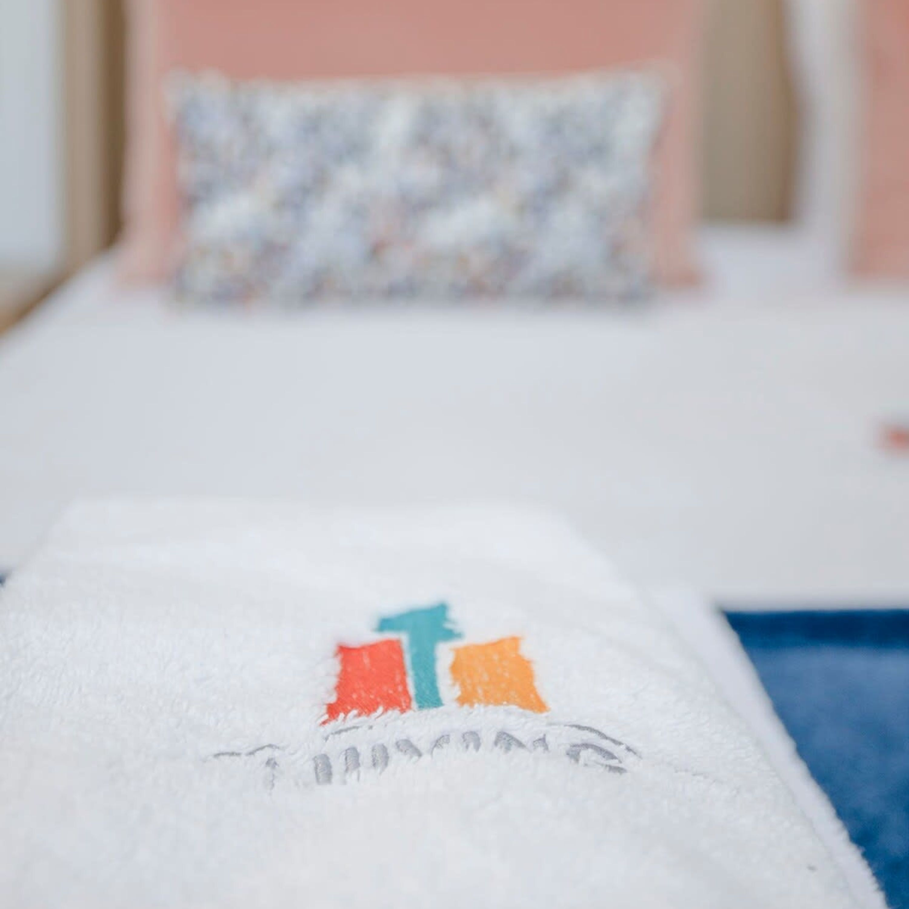 Ein Bett mit weißer Decke und einem Kissen mit farbigem Muster.