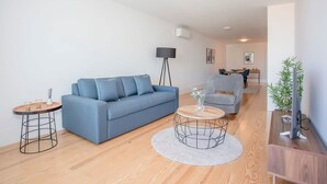 Un salon moderne avec un canapé bleu, une table basse ronde et un fauteuil gris.