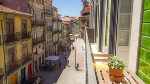 Eine schmale Straße mit Häusern an beiden Seiten, Außenbereichs-Gastronomie und ein Blumentopf auf der rechten Seite.