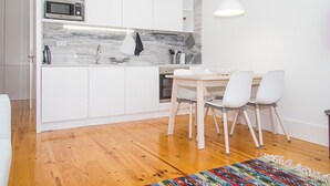 Eine moderne Küche mit weißen Schränken, einer Marmor-Spritzschutzwand und einem Holzespeisetisch mit vier Stühlen.