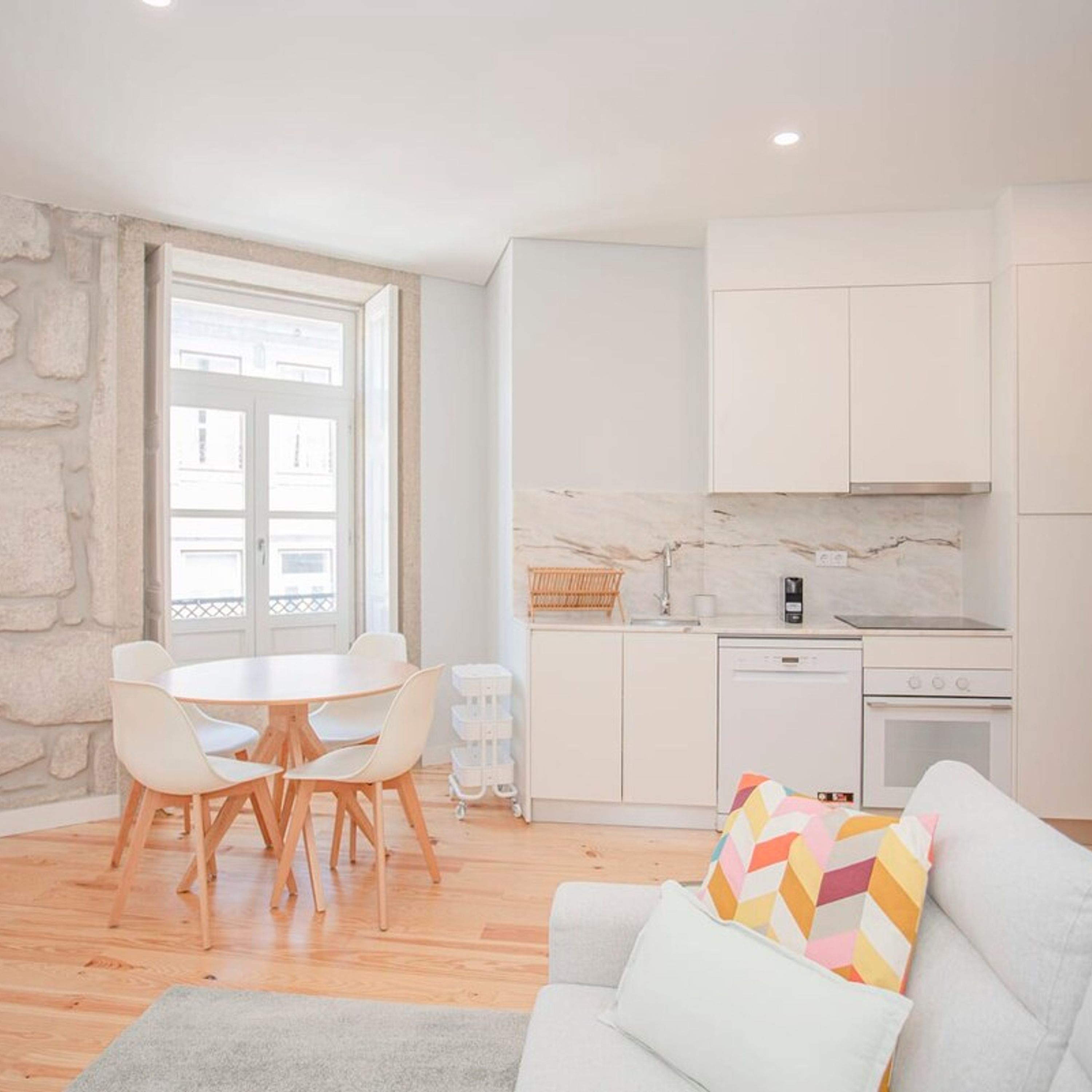 A modern kitchen with white cabinets, a marble backsplash, and a built-in oven.