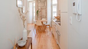 Una cucina moderna con parete in pietra, pavimento in legno e zona pranzo con tavolo e sedie.