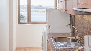Una cucina moderna con mobili in legno, un lavello in acciaio inossidabile e vista sul mare.