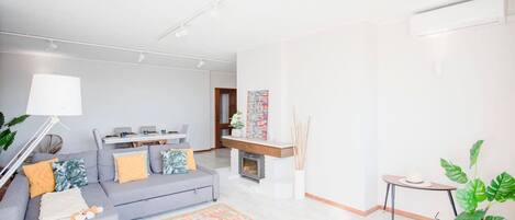 Un soggiorno moderno con un divano grigio, un tappeto decorato e un tavolino con una pianta.