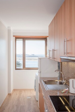 Una cocina moderna con armarios de madera, un lavamanos de acero inoxidable y vistas al mar.