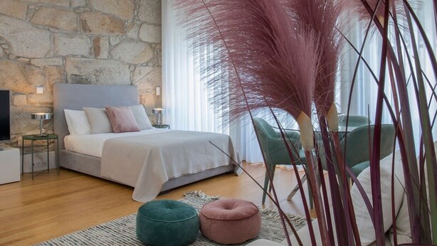 Une chambre avec un mur en pierre, un lit, une télévision et une fenêtre avec des rideaux.