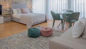 Une chambre avec un mur en pierre, un lit, une table de chevet, une télévision et une fenêtre ornée de rideaux légers.