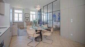 Una cucina moderna con zona pranzo, con un tavolo rotondo e sedie, una lampada a sospensione e un'ampia finestra.
