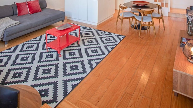 Ein modernes Loft mit hohen Decken, einer Wendeltreppe zu einer erhöhten Ebene, einer Küchenzeile und einer Sitzecke mit Sofa und Esstisch.