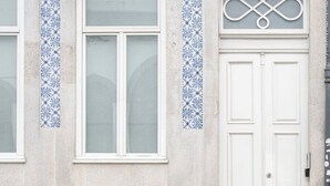 Ein Gebäude mit einer weißen Tür, einem Fenster und einem Balkon mit blauen Fliesen.