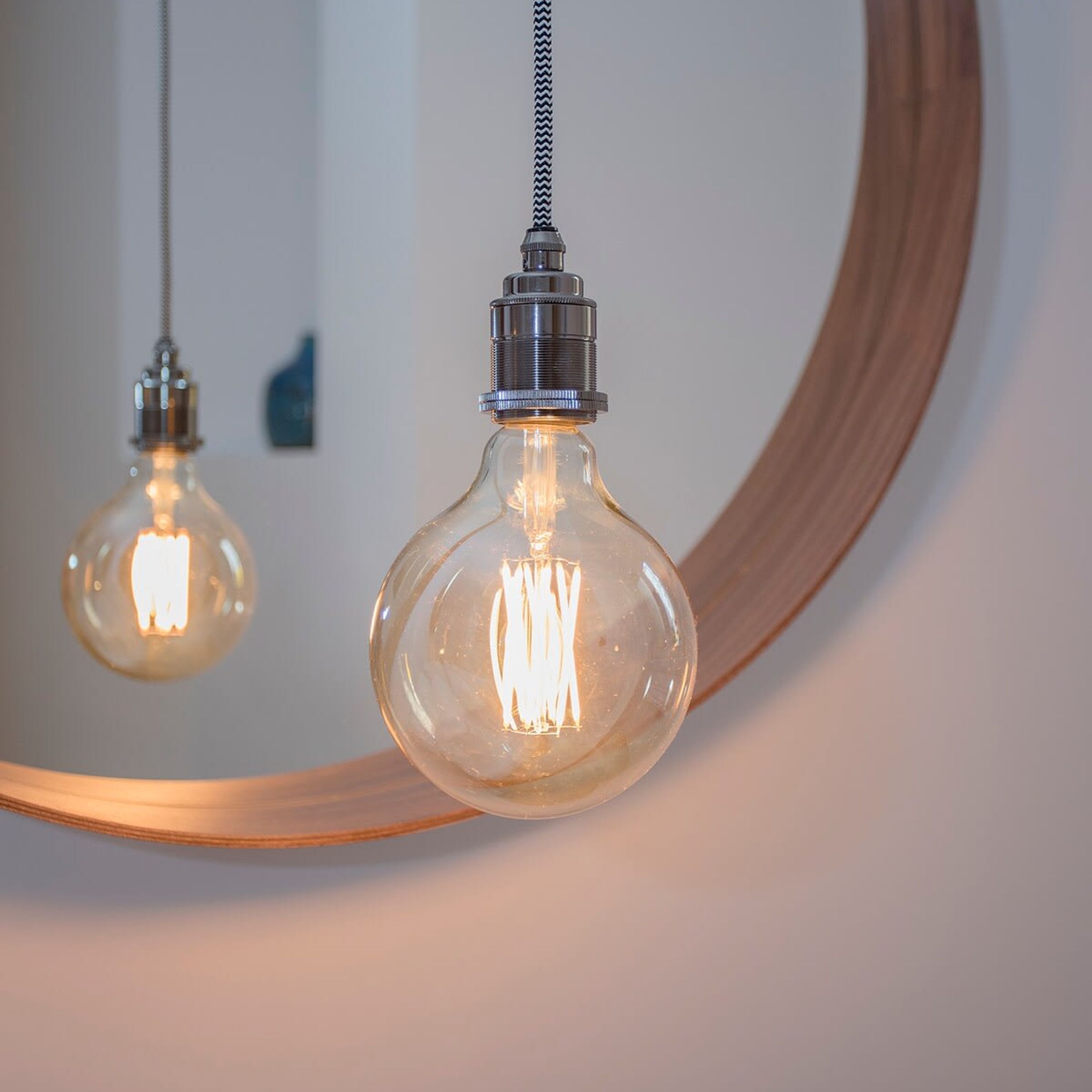 A light bulb with a metallic base and a clear glass enclosure, suspended by a cord.