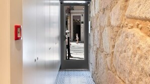 Un couloir doté d’un sol à motifs géométriques, d’un mur en pierre d’un côté et d’une porte donnant sur une autre pièce.