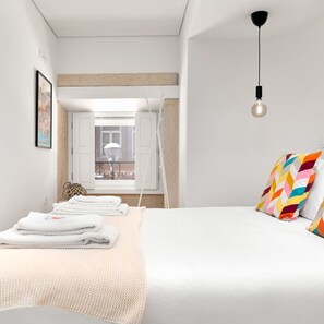 Une chambre à coucher moderne avec un lit, une fenêtre et un luminaire suspendu.