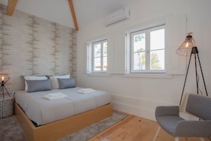 Une chambre à coucher avec un lit, une chaise et deux fenêtres.