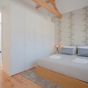 Ein Schlafzimmer mit einem Bett, einem weißen Kleiderschrank und einem Nachttisch mit Lampe.
