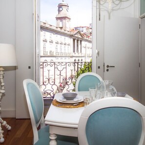 Ein Balkon mit Tisch für zwei Personen, Blick auf eine Stadtlandschaft mit historischen Gebäuden und einem Glockenturm.
