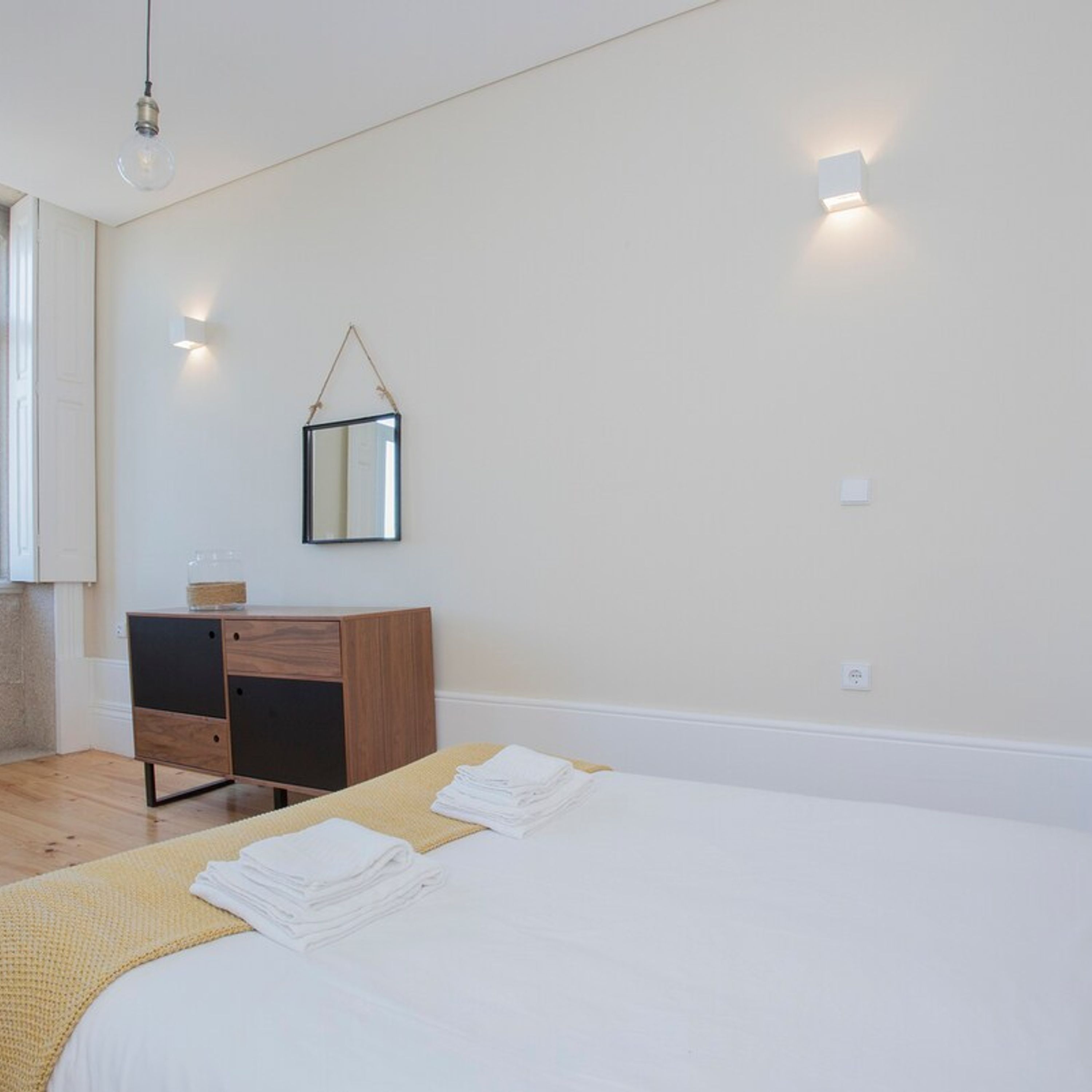 Ein Schlafzimmer mit einem Bett, einem Schminktisch, einem Wandspiegel und einer Lampe.