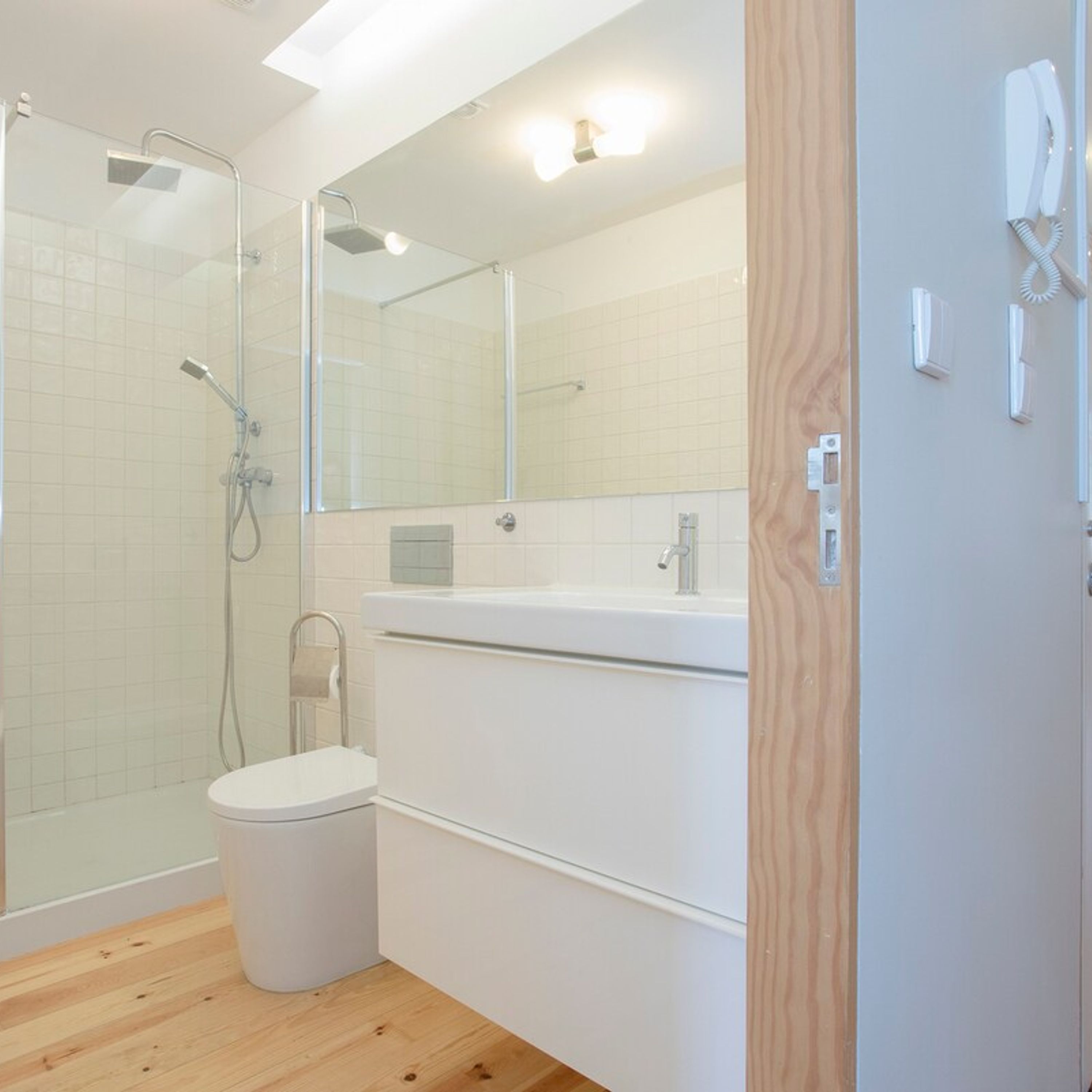 A modern bathroom with a glass-enclosed shower, a white toilet, and a vanity with a mirror.