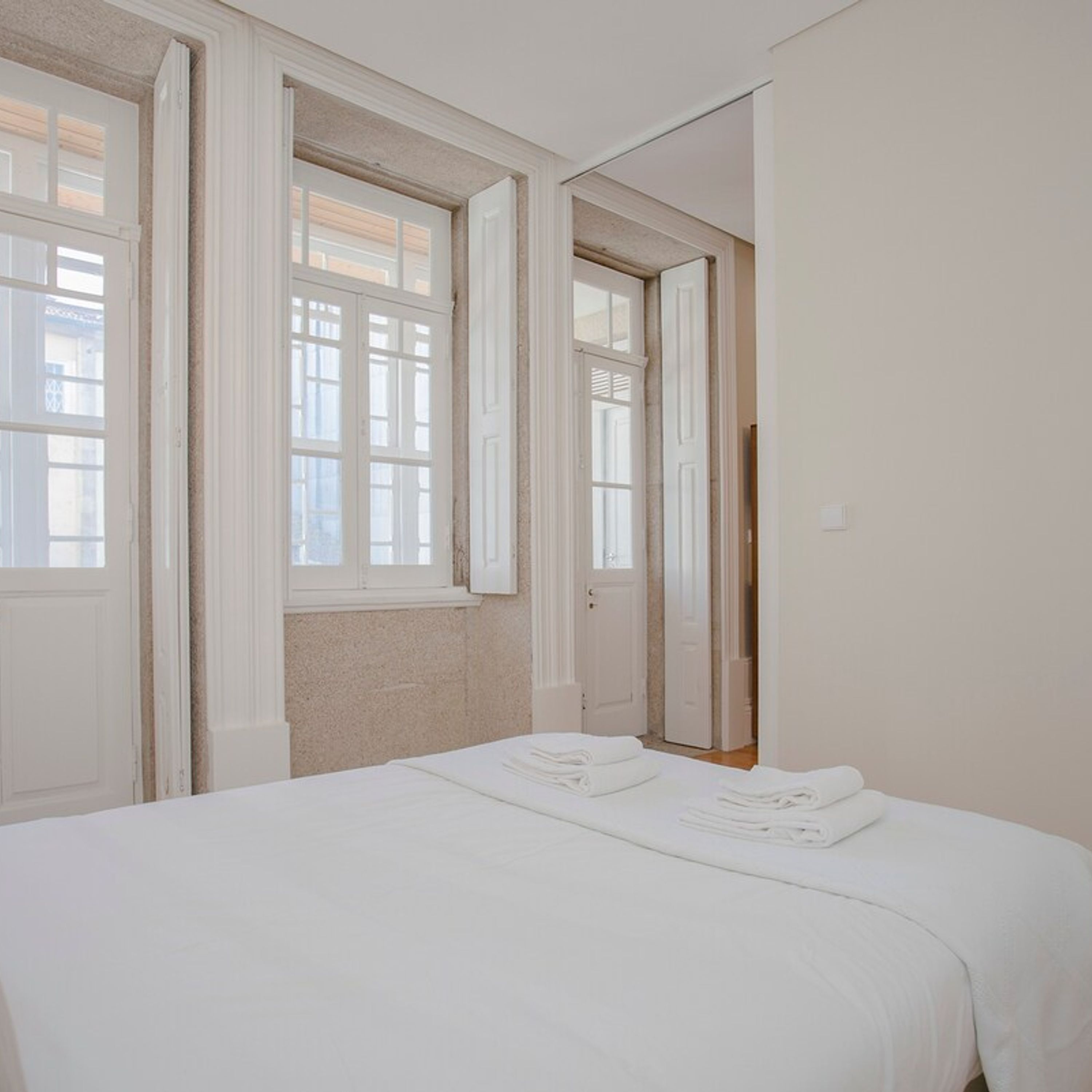 A bedroom with a bed, a window, and a door.