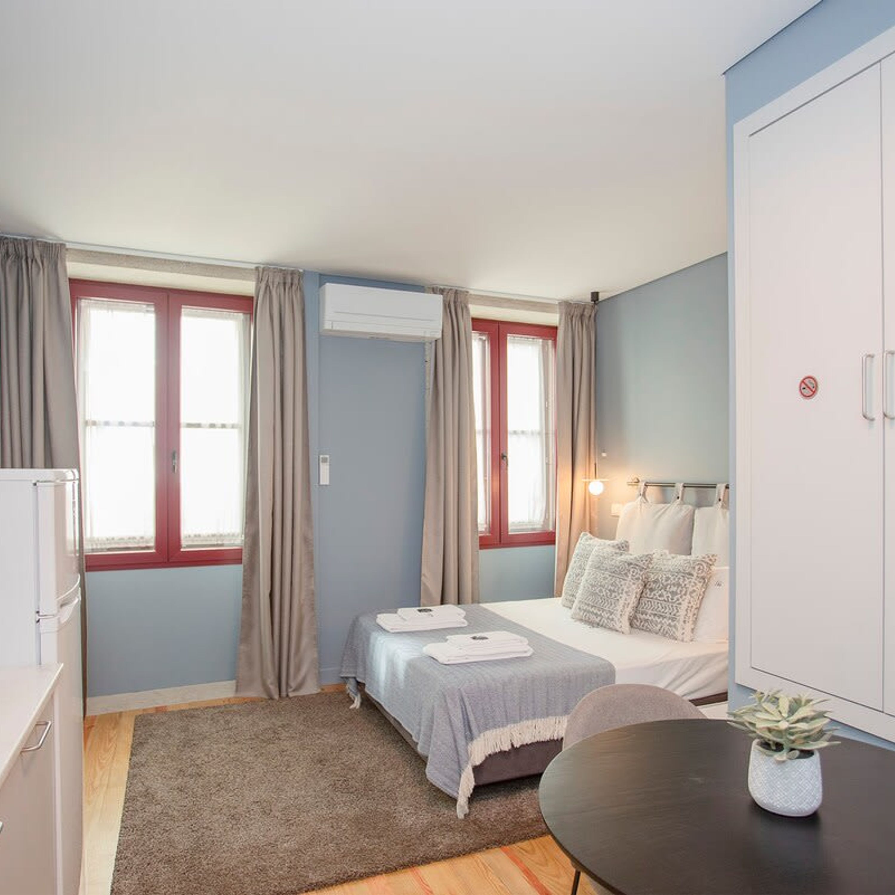 A compact hotel room with a bed, a desk, and a wardrobe.