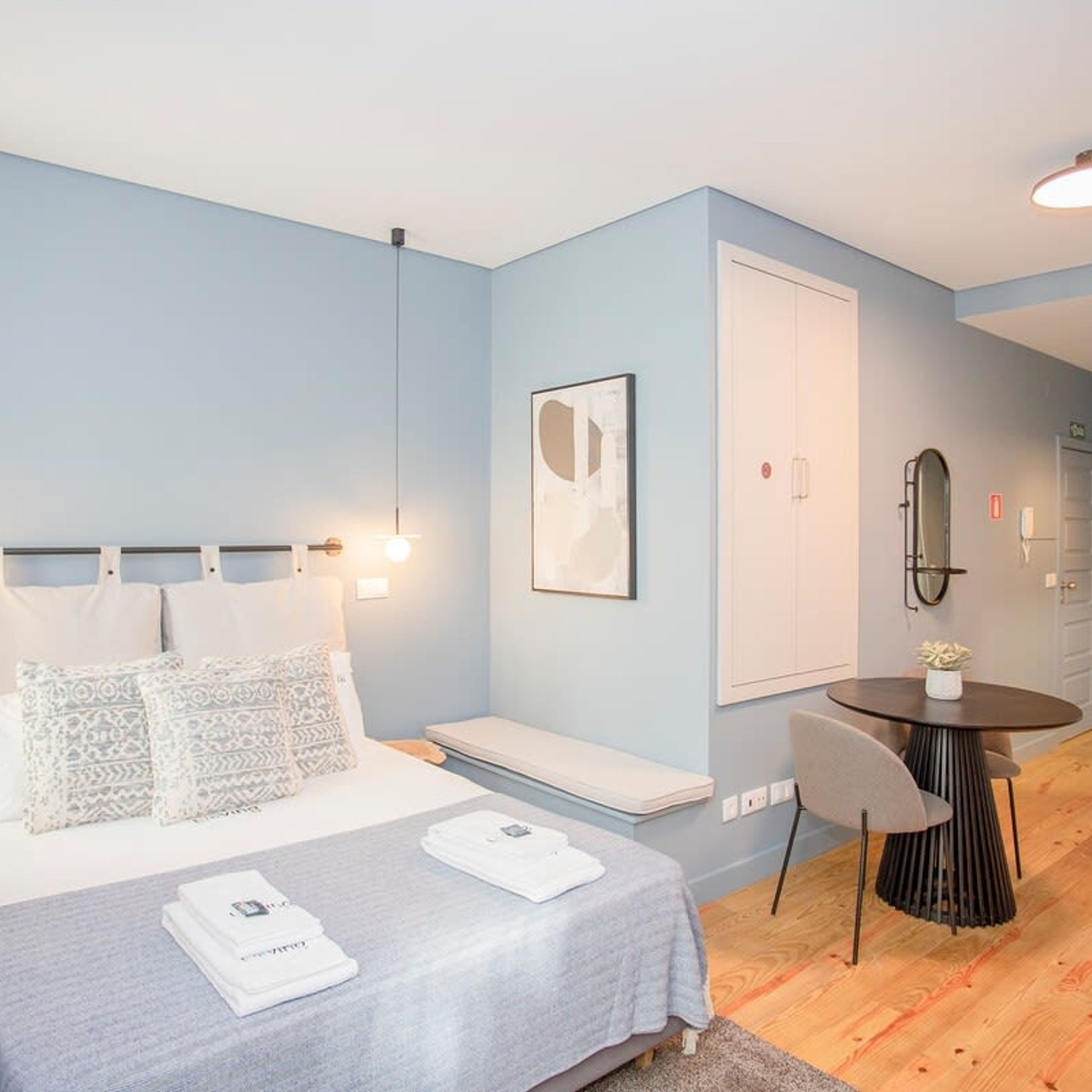 A modern bedroom with a bed, bedside tables, a desk, and a chair.