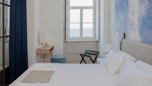 A hotel room with a bed, a desk, a chair, and a window with a view. - Liiiving in Porto Luxury Beachfront Apartment II (Porto)