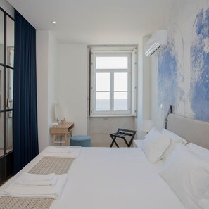 A hotel room with a bed, a desk, a chair, and a window with a view. - Liiiving in Porto Luxury Beachfront Apartment II (Porto)