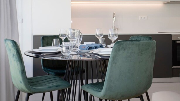 A modern dining area with a round table set for four, surrounded by four green upholstered chairs. - Liiiving in Porto-modern Glam Rooftop Apartment (Porto)