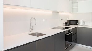 A modern kitchen with white cabinetry, a stainless steel sink, and a built-in oven. - Liiiving in Porto-modern Glam Rooftop Apartment (Porto)
