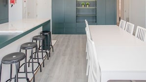A modern kitchen with a white countertop, bar stools, and a built-in shelving unit. - Liiiving in Porto - Ribeira Riverside Apartment (Porto)