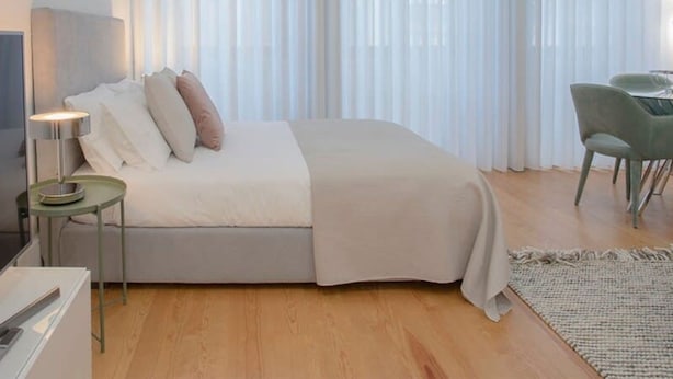 A modern bedroom with a bed, bedside table, lamp, and a chair. - Liiiving in Porto Downtown Luxury Apartment 1R (Porto)