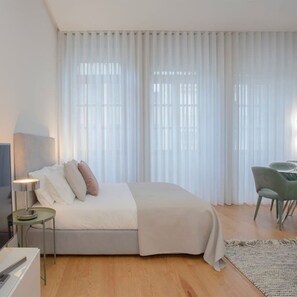 A modern bedroom with a bed, bedside table, lamp, and a chair. - Liiiving in Porto Downtown Luxury Apartment 1R (Porto)