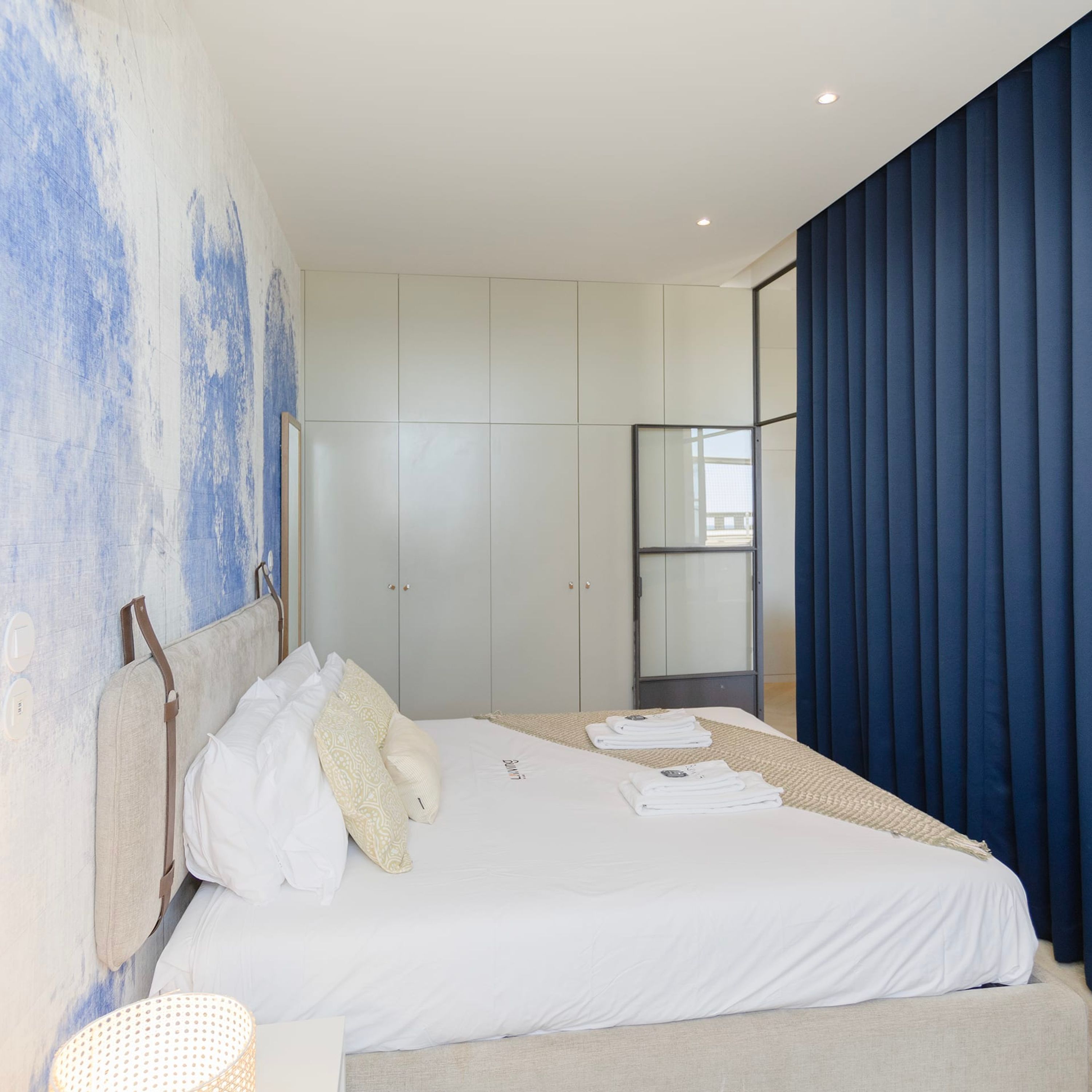 Une chambre à coucher moderne avec un grand lit, une armoire et un miroir.