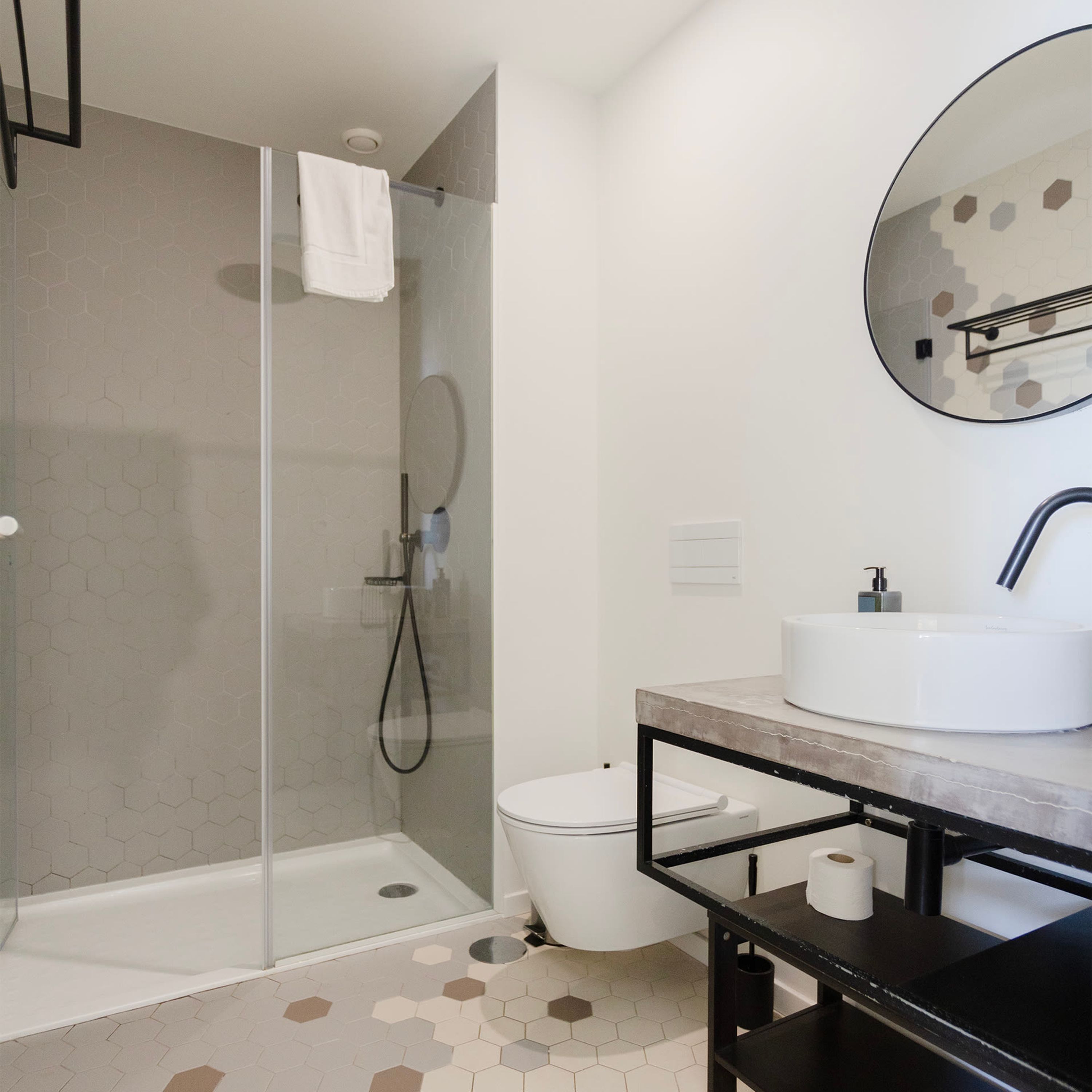 A modern bathroom with a glass-enclosed shower, a white toilet, and a sink with a mirror above it.