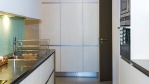 A modern kitchen with white cabinets, a stainless steel countertop, and a built-in oven. - Liiiving in Matosinhos - High Sea Condo (Matosinhos)