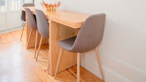A dining area with a wooden table, four chairs, and pendant lights. - Liiiving in Porto - Ribeira Secret Apartment (Porto)