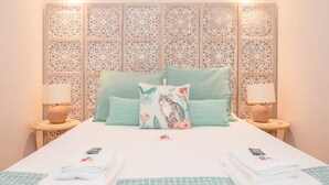 A neatly made bed with a patterned bedspread, two pillows, and folded towels on the bed. - Liiiving in Porto - Ribeira Secret Apartment (Porto)