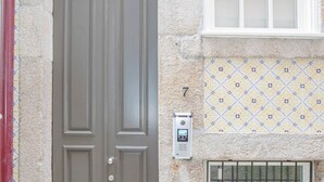 A gray double door with a keypad lock, a window with a grid pattern, and a number '7' on the wall. - Liiiving in Porto - Ribeira Secret Apartment (Porto)