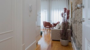 Ein modernes Wohnzimmer mit einer Couch, einem Essbereich mit Stühlen und einem großen Fenster mit Vorhängen.