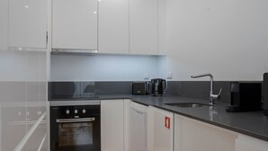 Eine moderne Küche mit weißen Schränken, einem Edelstahlherd, einem Geschirrspüler und einer Kaffeemaschine.