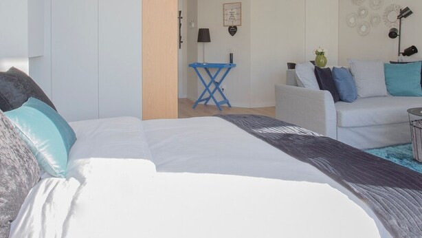 A modern bedroom with a large bed, a small desk, and a sofa. - Liiiving in Porto Bright Light Studio (Porto)