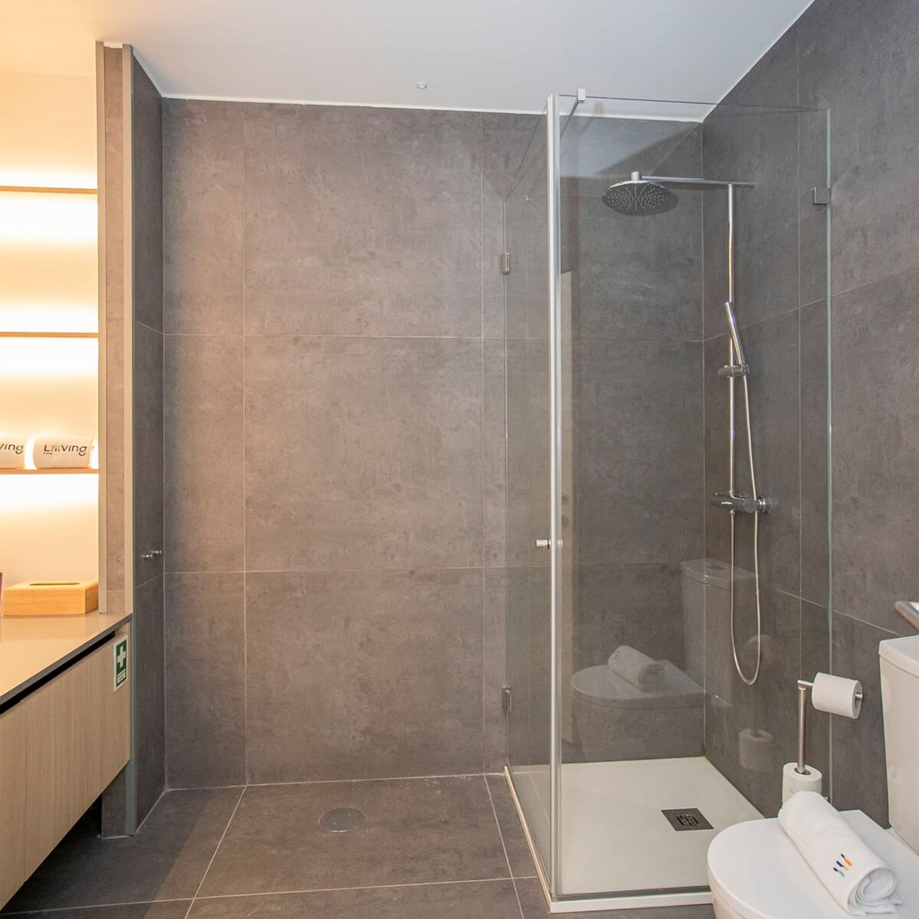 Un baño moderno con ducha acristalada, inodoro y lavabo.