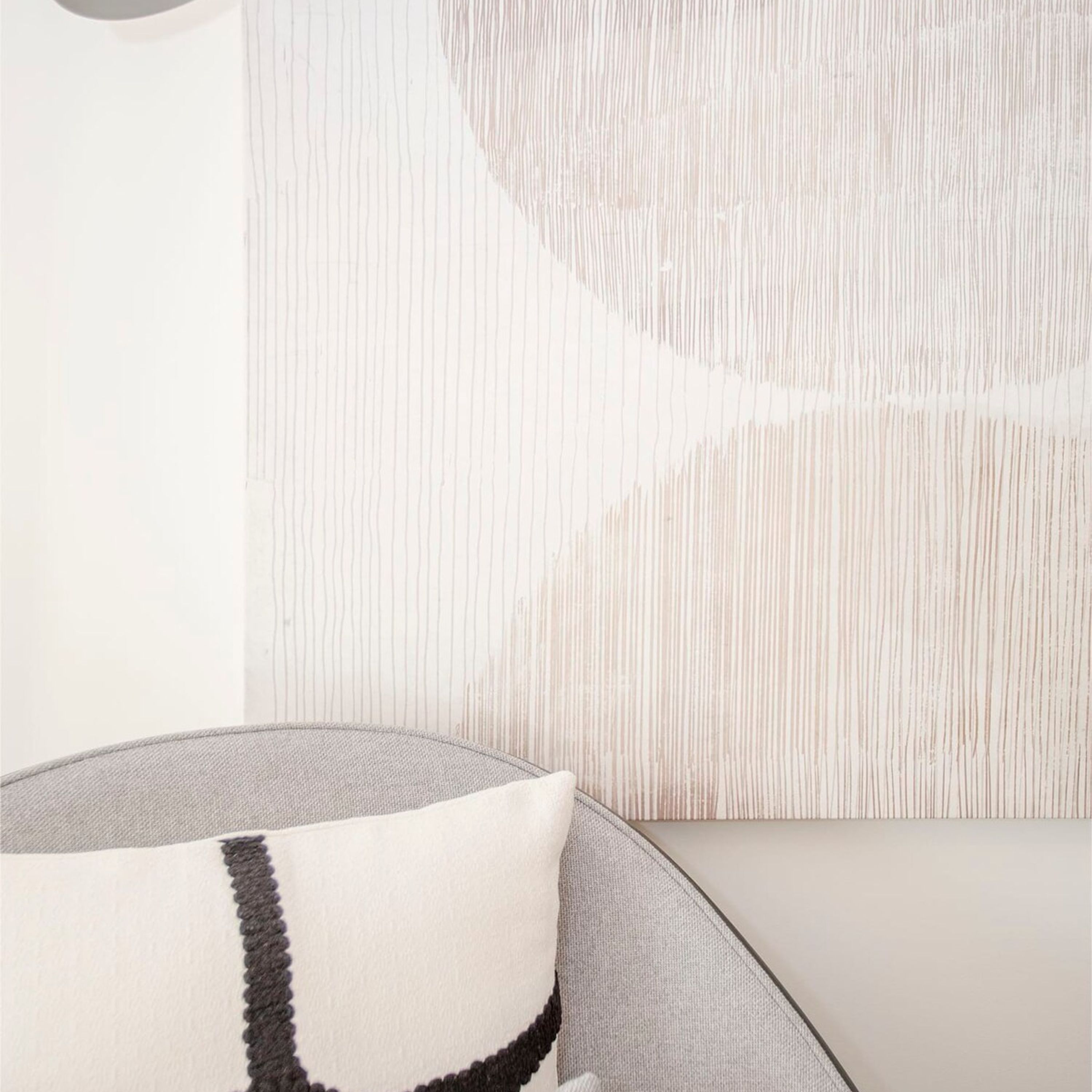 A modern living room with a sofa and a round, textured ottoman.