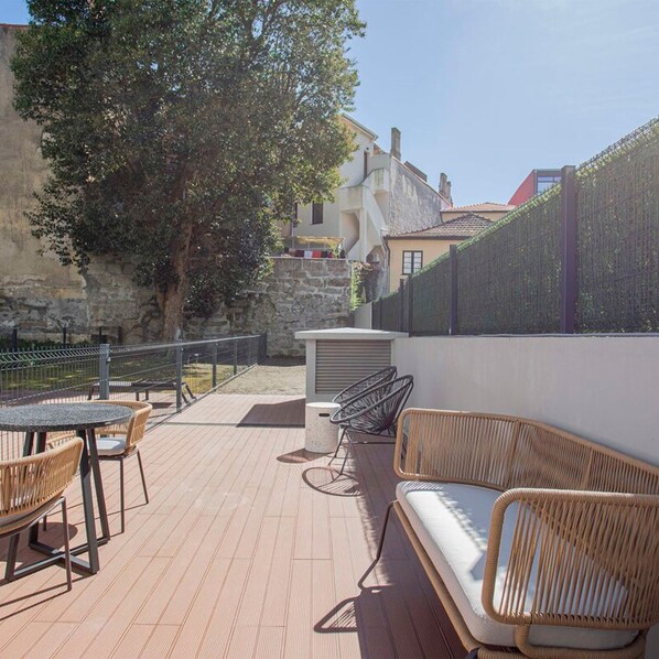 An outdoor patio with wicker furniture, a table, and a seating area. - Liiiving in Porto - City Design Apartment A (Porto)
