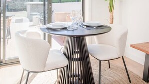 A dining area with a round table, white chairs, and a potted plant. - Liiiving in Porto - City Design Apartment A (Porto)