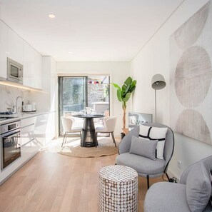 A modern kitchen with a dining area, a sofa, and a large window. - Liiiving in Porto - City Design Apartment A (Porto)