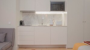 A compact kitchen with white cabinets, a microwave, and a coffee maker. - Liiiving in Porto Charming Downtown Delight I (Porto)